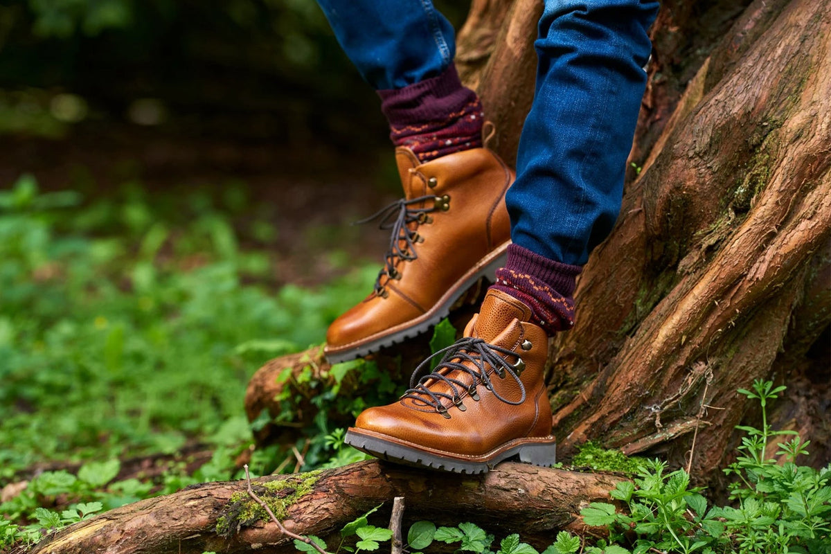 Brown boots on a person standing on a log in a forest setting