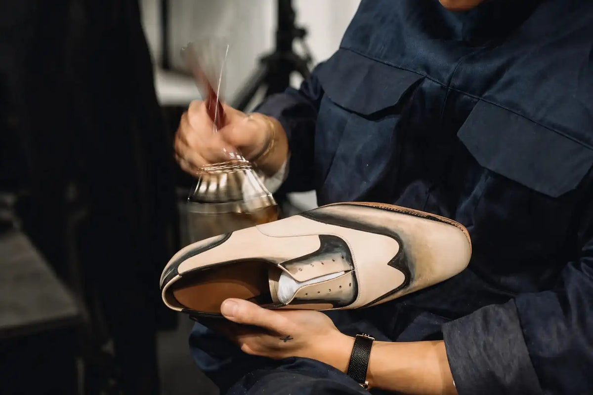 Person holding a beige and brown shoe with a blurred background